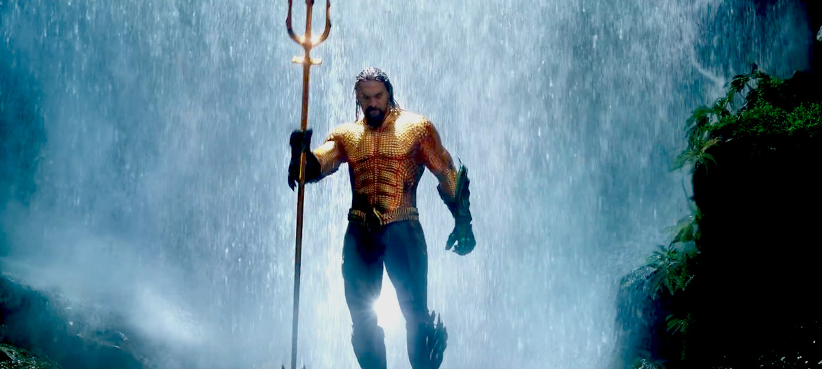 Aquaman - Aquaman tenant un trident debout devant une cascade
