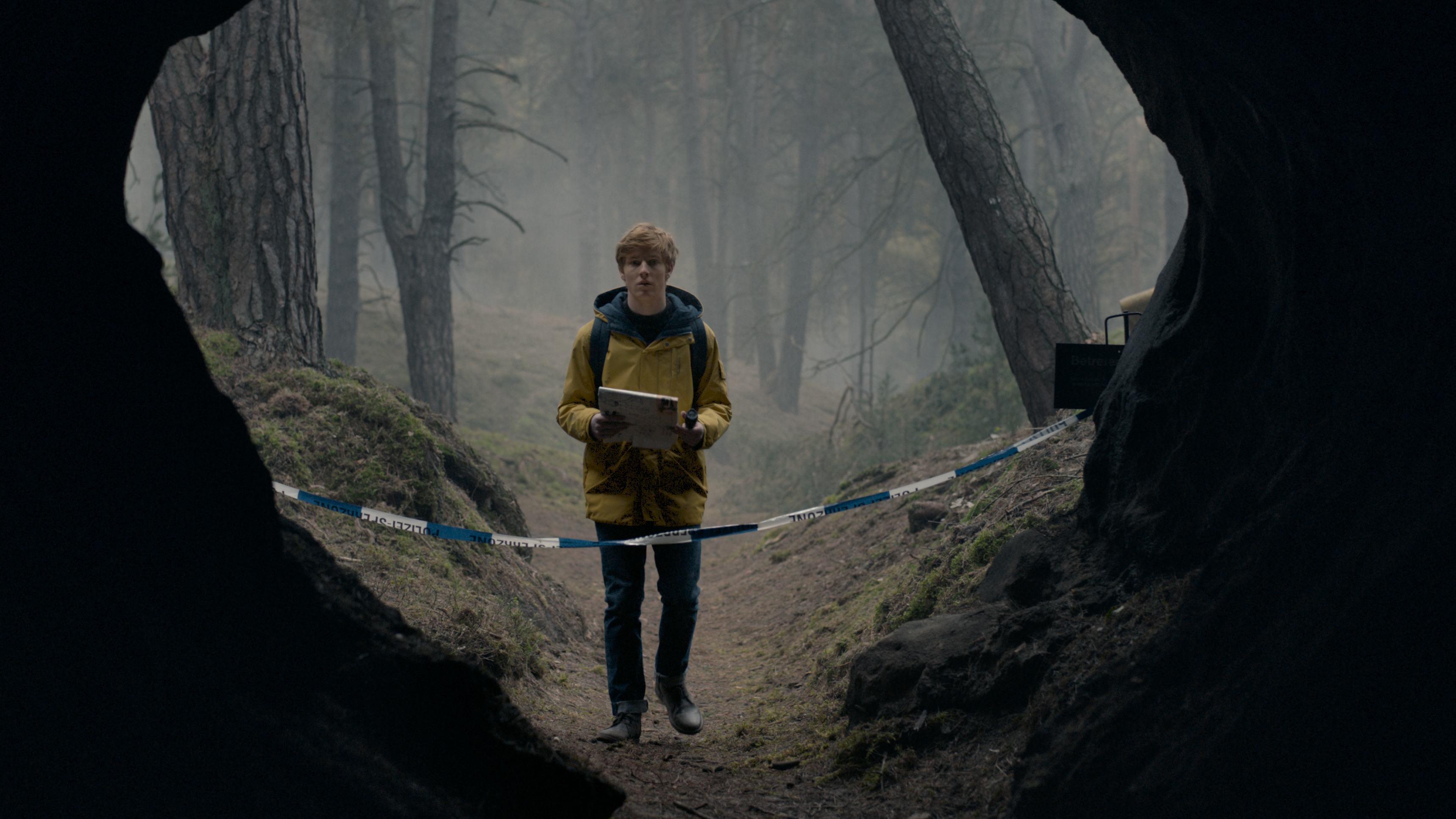 Jonas Kahnwald (Louis Hofmann) regarde dans une grotte qui a été bloquée par une bande de mise en garde dans Netflix's Dark.