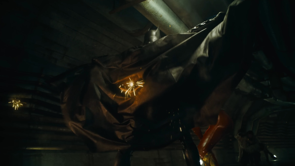 Batman étend sa cape, des balles étincellent alors que le ricochet s'en échappe dans The Flash
