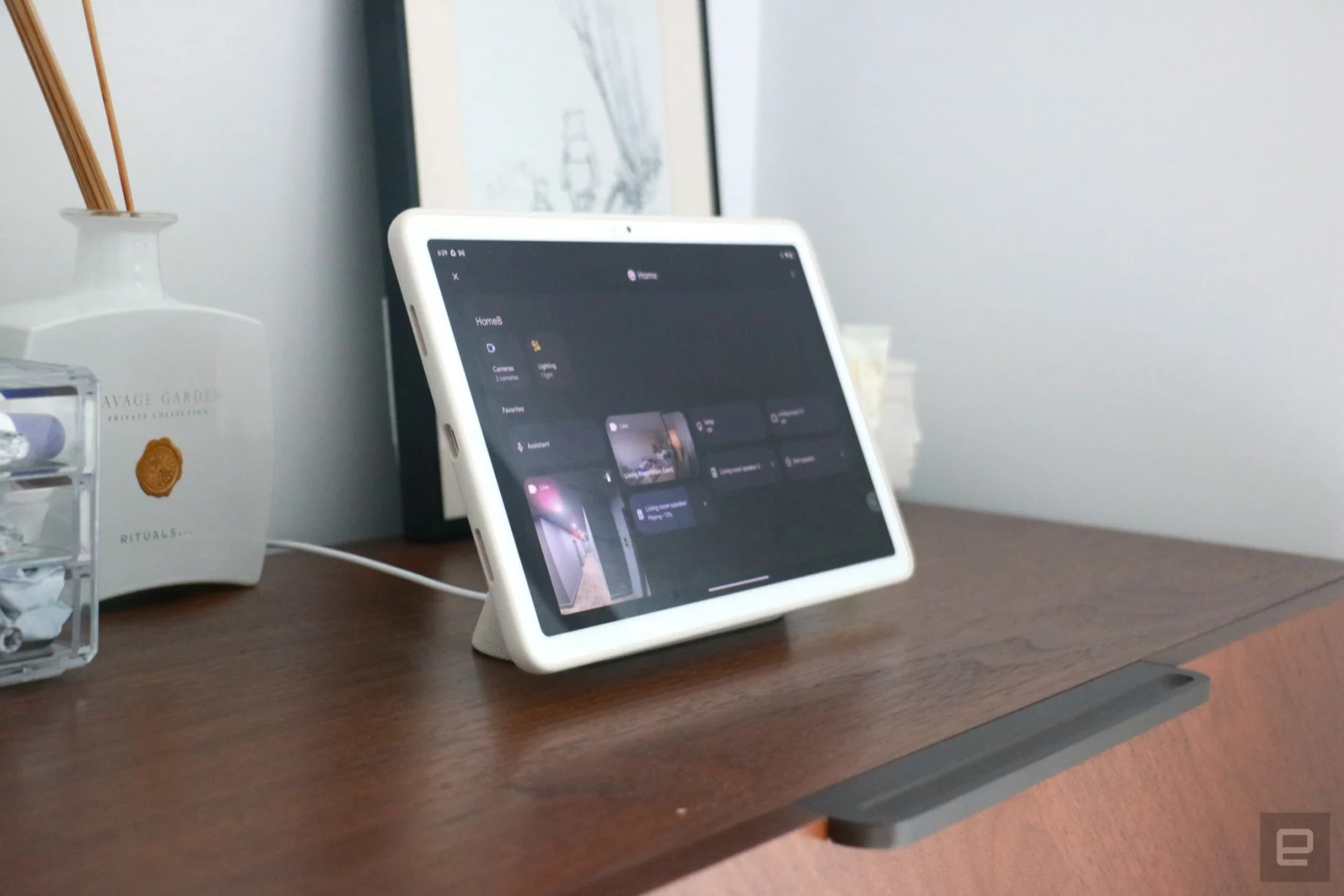 La tablette Pixel sur une commode en noyer montrant le tableau de bord de la maison intelligente en mode Hub.