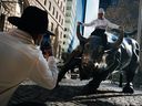 Un homme est assis sur le taureau de Wall Street près de la Bourse de New York à New York.