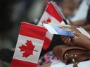 Des gens tiennent des drapeaux canadiens lors d'une cérémonie d'immigration à Toronto.  La semaine dernière, le Canada a dépassé les 40 millions d'habitants pour la toute première fois.
