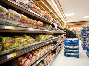 Un travailleur réapprovisionne les étagères de l'allée de la boulangerie et du pain dans une épicerie à Halifax.