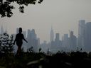 Un piéton marchant le long du front de mer à West New York, New Jersey, le 8 juin 2023, alors que la brume de fumée des incendies de forêt canadiens recouvre la région.