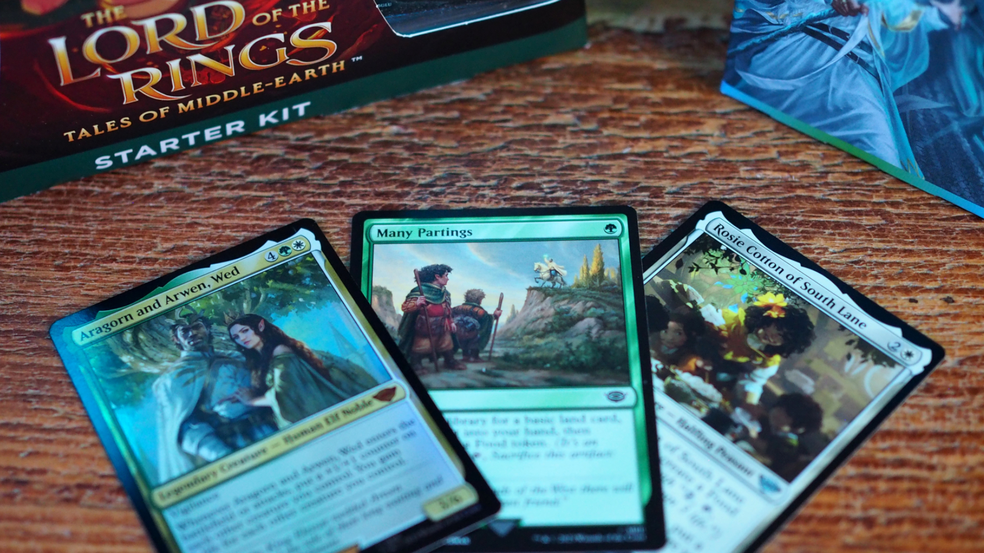 Trois cartes sur une table en bois du MTG Lord of the Rings Starter Set