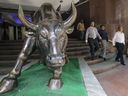 Les gens passent devant la statue de taureau en bronze à l'entrée du bâtiment de la Bourse de Bombay à Mumbai, en Inde.  Les actions indiennes sont sous-estimées, disent les analystes.