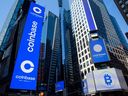 Les moniteurs affichent la signalisation Coinbase lors de l'introduction en bourse de la société au Nasdaq MarketSite à New York, aux États-Unis, le 14 avril 2021. 