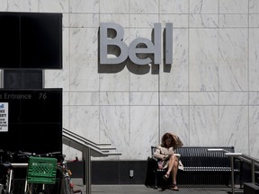 Une femme lit devant un bureau de Bell Canada à Toronto.