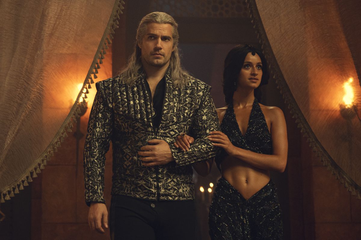 Geralt (Henry Cavill) et Yennefer (Anya Chalotra) entrent dans le conclave des mages bras dessus bras dessous portant leurs plus belles tenues de soirée dans The Witcher.
