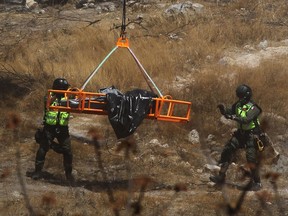 Des experts médico-légaux travaillent avec plusieurs sacs de restes humains extraits du fond d'un ravin par un hélicoptère à Zapopan, dans l'État de Jalisco, au Mexique, le 31 mai 2023.