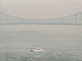 Un bateau passe par le pont Jacques-Cartier obscurci par une brume de smog à Montréal, dimanche 25 juin 2023, alors qu'un avertissement de smog est en vigueur pour la ville et plusieurs régions de la province en raison d'incendies de forêt.  De l'air enfumé et dangereux se dépose sur certaines parties de l'ouest du Québec et de l'est de l'Ontario ce matin et le nombre d'incendies de forêt qui brûlent à travers le Canada augmente encore une fois.