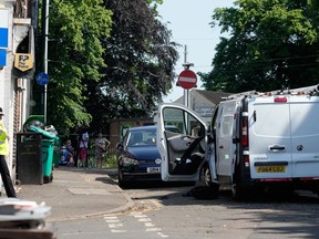 Les gens regardent depuis une clôture alors qu'un policier garde une zone de la route de Bentinck près d'une camionnette qui est potentiellement liée à un incident majeur survenu plus tôt dans la journée le 13 juin 2023 à Nottingham, en Angleterre.