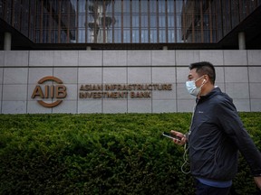 Un homme passe devant le logo de la Banque asiatique d'investissement dans les infrastructures (AIIB) au siège à Pékin.