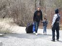 Des demandeurs d'asile entrent au Canada depuis la frontière américaine près d'un point de contrôle sur le chemin Roxham près de Hemmingford, Québec, Canada, le 24 avril 2022. 
