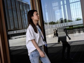 Une femme passe devant le portail du siège de la Banque asiatique d'investissement dans les infrastructures (AIIB) à Pékin le 15 juin 2023.