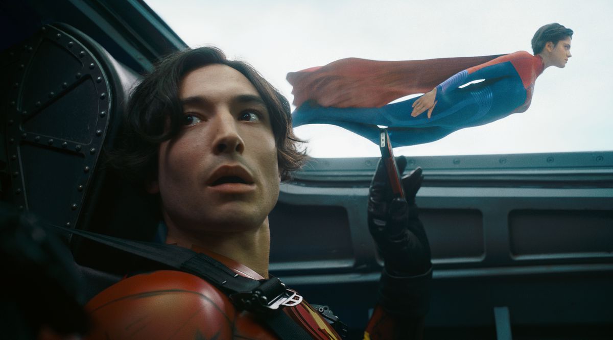 Ezra Miller dans le rôle de Young Barry a l'air maladroit alors qu'il prend une vidéo de téléphone portable de Supergirl de Sasha Calle volant près de l'avion dans lequel il se trouve dans The Flash.