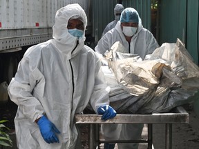 Des employés médico-légaux transportent les cadavres de plusieurs des 46 femmes décédées lors d'un incendie suite à une rixe entre détenues de la prison du Centre d'adaptation sociale des femmes (CEFAS) à la morgue pour pratiquer son autopsie à Tegicugalpa, le 21 juin 2023.