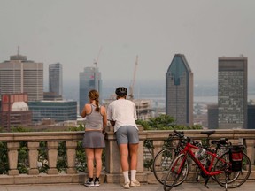 Les gens regardent la ville de Montréal enveloppée dans la fumée des incendies de forêt qui brûlent au nord de Québec.