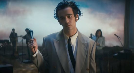 Matty Healy holding a mic in the Part of the Band performance by The 1975.