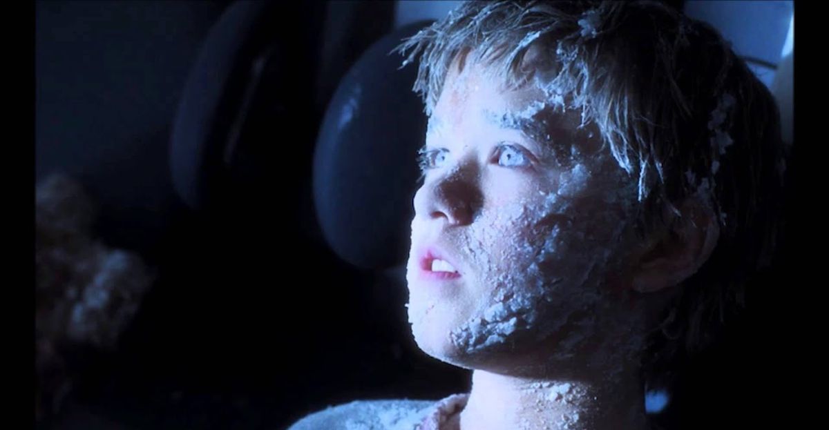 Le robot David, qui ressemble à un petit enfant (joué par Haley Joel Osment) avec de la glace dans les cheveux, sur le visage et dans les yeux dans AI Artificial Intelligence de Steven Spielberg