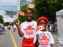 Makalah, 9 ans, et son frère Sawlah, 7 ans, posent pour une photo après s'être fait tatouer temporairement la feuille d'érable à la foire de rue d'East Village lors des célébrations de la fête du Canada le vendredi 1er juillet 2022.
