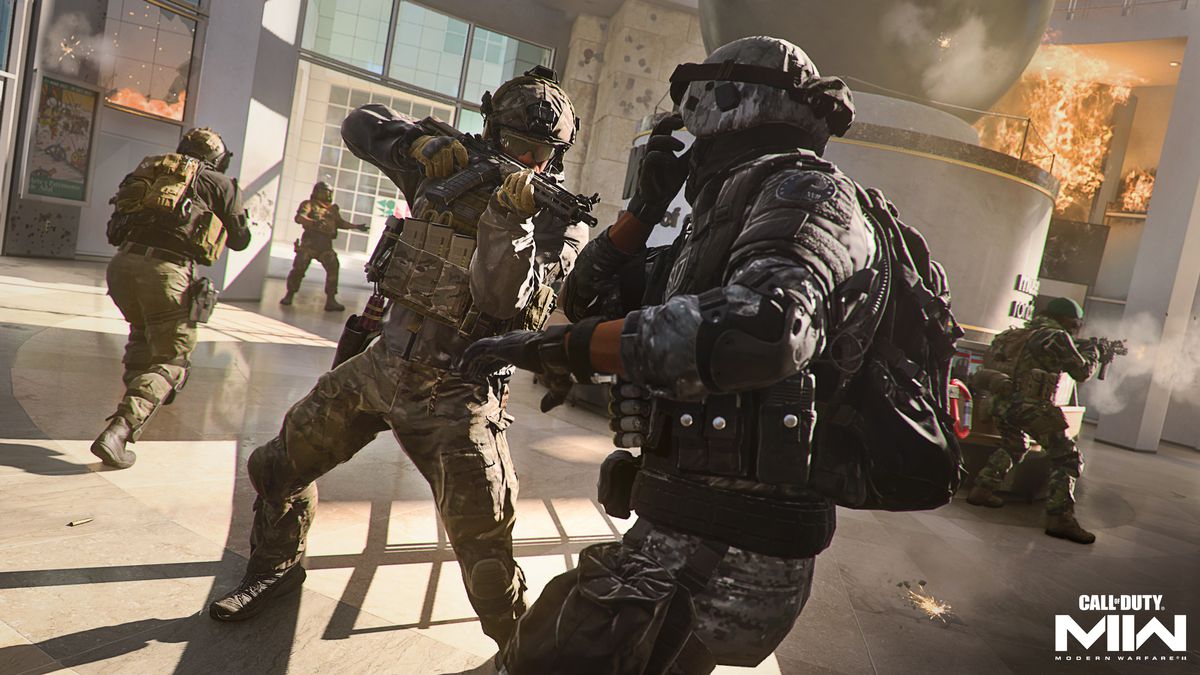 Un joueur pointe une mitraillette sur un adversaire à l'intérieur d'un immeuble de bureaux en feu dans une capture d'écran de Call of Duty: Modern Warfare 2