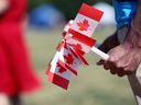 Un bénévole tient des drapeaux souvenirs à distribuer dans un parc de Winnipeg le 1er juillet 2019. 
