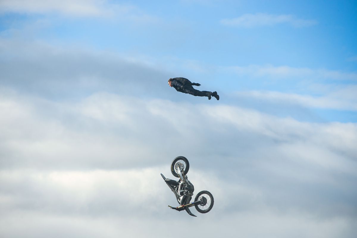 Tom Cruise s'envole dans le ciel alors que la moto sur laquelle il se trouvait plonge dans les nuages ​​en dessous d'eux dans Mission : Impossible - Dead Reckoning Part 1