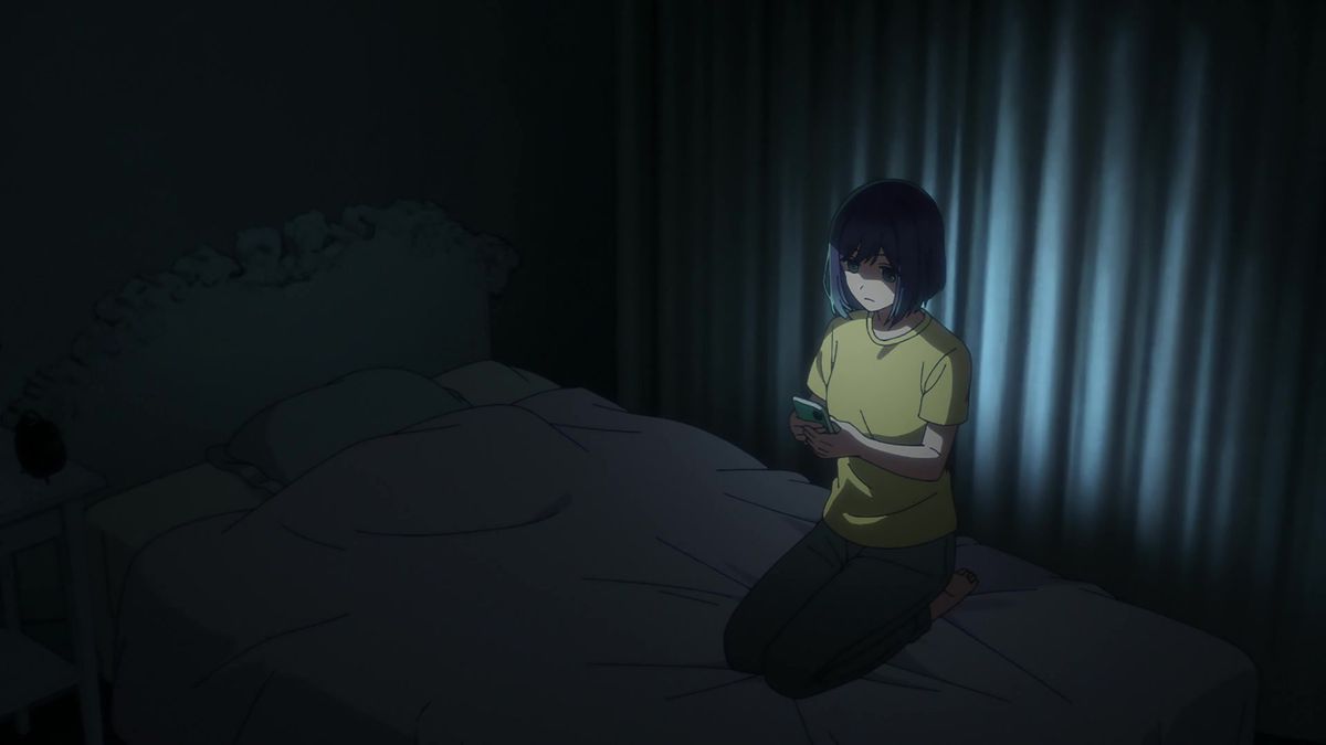 Akane dans une pièce sombre éclairée uniquement par l'écran de son téléphone alors qu'elle a l'air triste dans une photo d'Oshi No Ko
