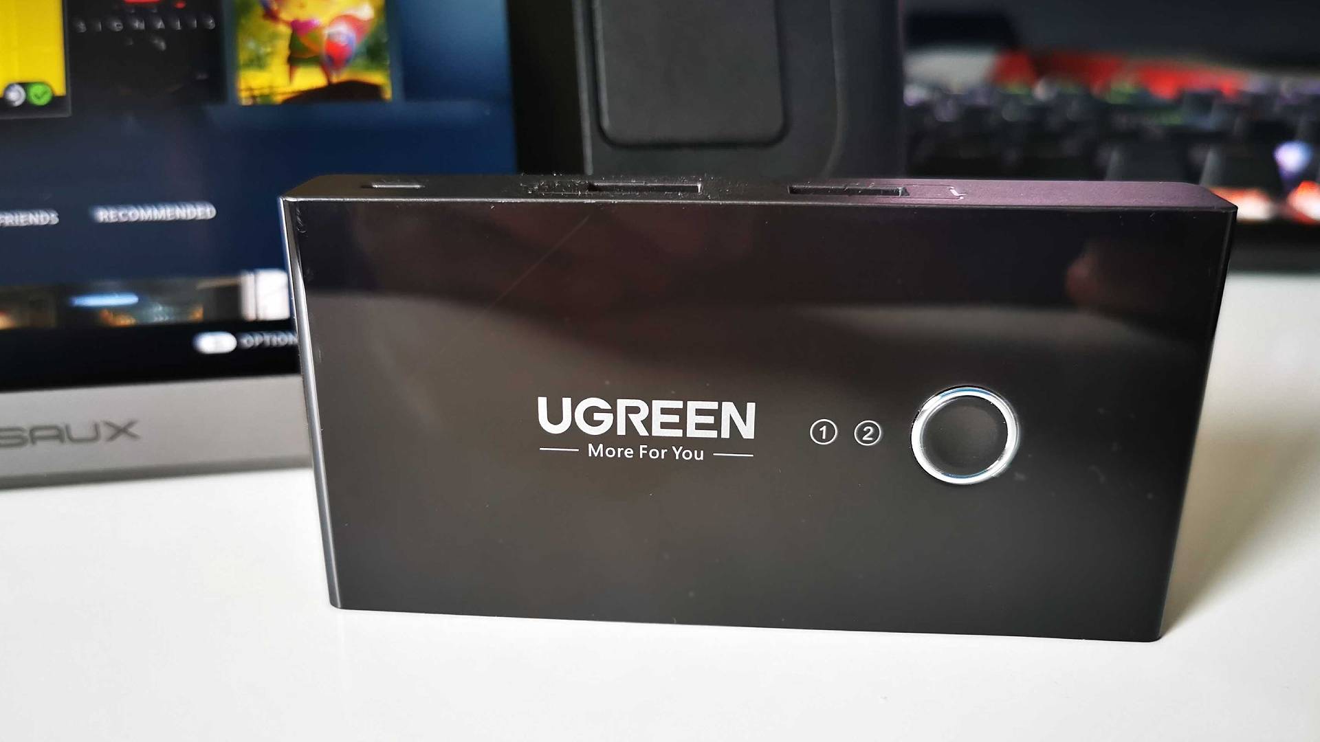 Commutateur USB Ugreen sur un bureau blanc avec écran Steam Deck en toile de fond