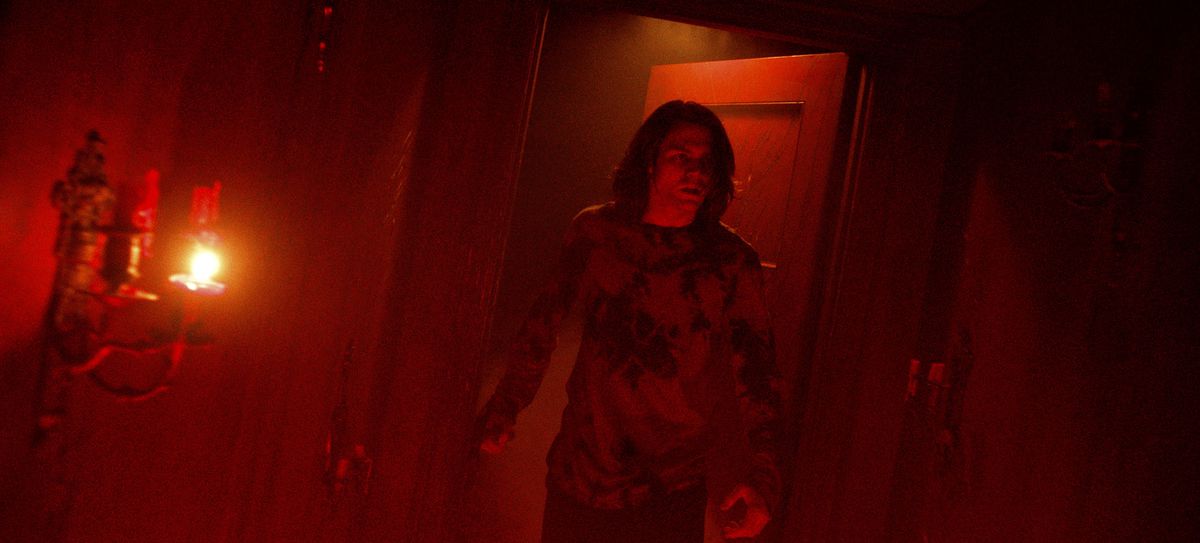 Dalton (Ty Simpkins), un adolescent grand, dégingandé et aux cheveux hirsutes, entre dans une pièce éclairée entièrement en rouge foncé dans Insidious: The Red Door