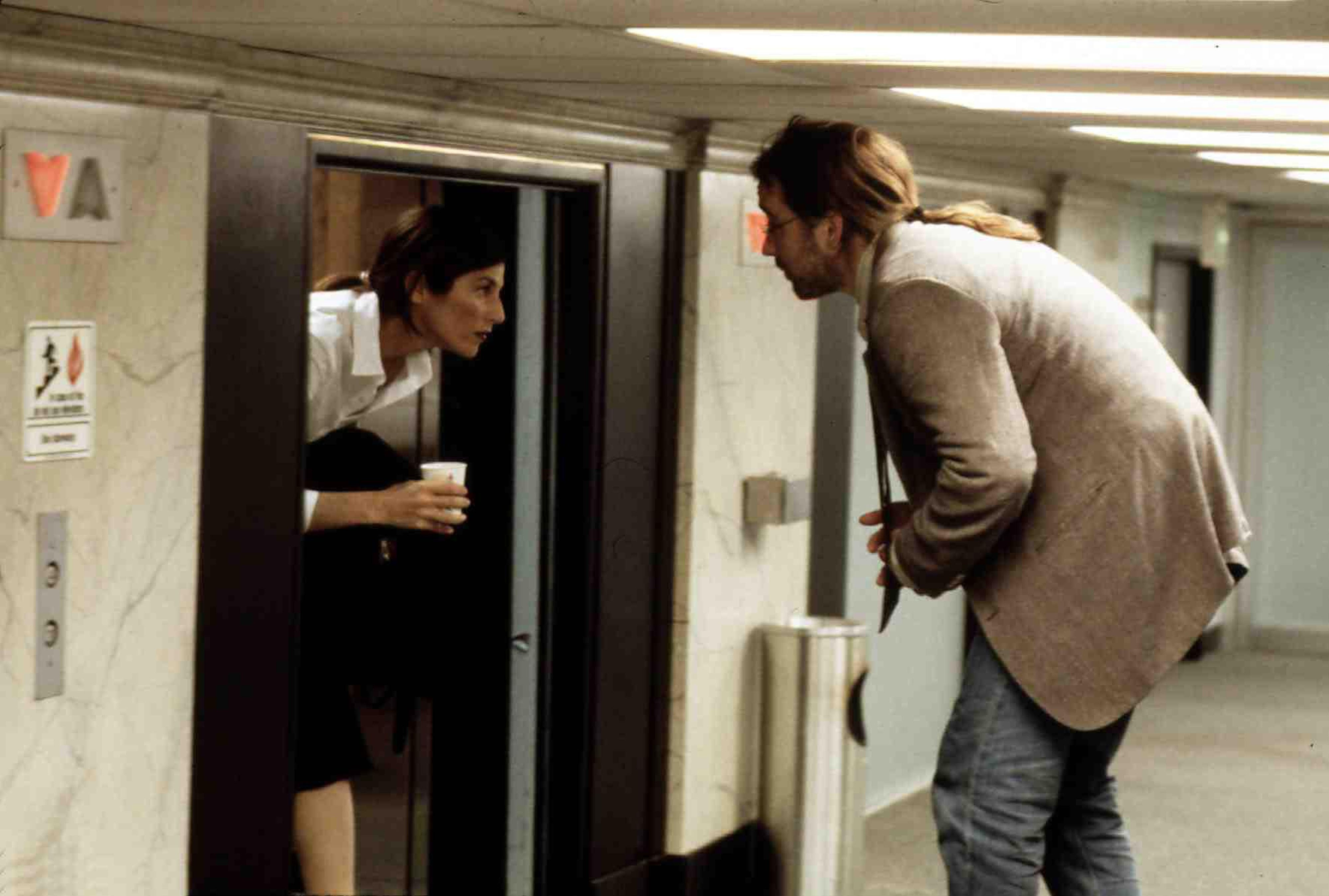 (De gauche à droite) Catherine Keener dans le rôle de Maxine et John Cusack dans le rôle de Craig à l'extérieur d'un ascenseur dans un couloir trop court qui les oblige à s'accroupir dans Being John Malkovich