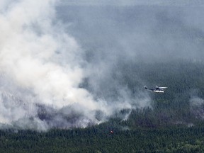 Un hélicoptère transportant une nacelle à eau survole un feu de forêt près de Lebel-sur-Quévillon, au Québec.