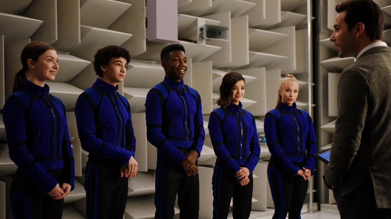 Le casting de Secret Society of Second Born Royals dans leurs uniformes bleus