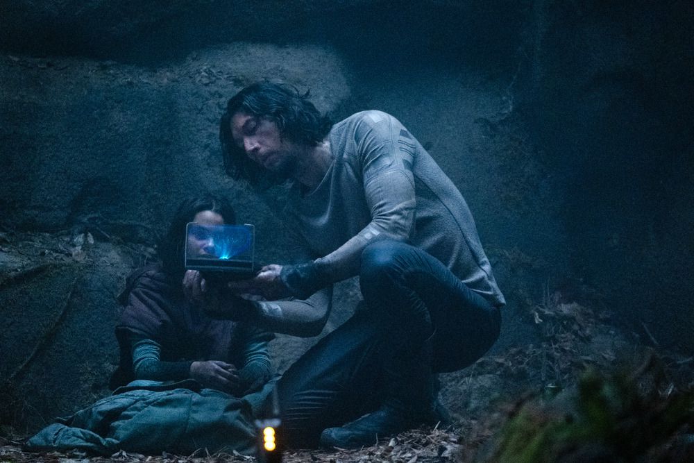 Koa (Ariana Greenblatt) assise dans une grotte sombre regardant un écran holographique Mills (Adam Driver) la montre en train d'utiliser son équipement en 65.