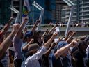 Des travailleurs portuaires en grève de l'International Longshore and Warehouse Union Canada lèvent le poing lors d'un rassemblement à Vancouver, le dimanche 9 juillet 2023. 