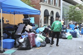 Les demandeurs d'asile avec tous leurs biens matériels ont continué à dormir dans la rue à l'extérieur du refuge de la ville de Toronto sur la rue Peter alors qu'ils attendaient un logement le vendredi 14 juillet 2023.