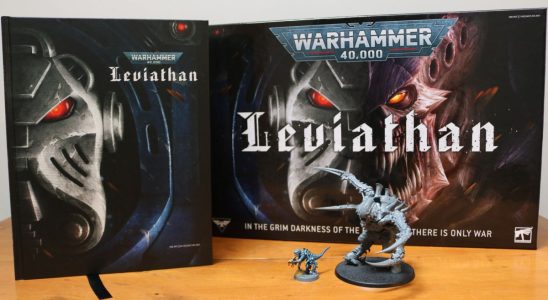 The Warhammer 40K Leviathan boxed set with the rule book and two miniatures set out on a wooden table