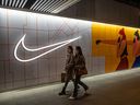 Des femmes passent devant un magasin Nike à Pékin, en Chine.  Le CORE enquêtera sur Nike Canada Corp. et Dynasty Gold Corp., une jeune société minière d'or, pour avoir prétendument bénéficié de l'utilisation du travail forcé ouïghour dans leurs chaînes d'approvisionnement et leurs opérations en Chine.