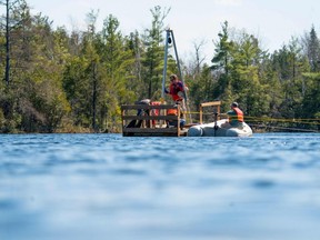 Tim Patterson (C), professeur de géologie à l'Université Carleton, à gauche, dirige une équipe de scientifiques alors qu'ils récupèrent une sonde au fond du lac Crawford tout en recueillant des échantillons de couches de sédiments au lac Crawford près de Milton, Ontario, Canada, 12 avril 2023 .