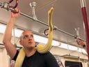 Un homme monte dans une rame de métro TTC avec un serpent enroulé autour de son corps.