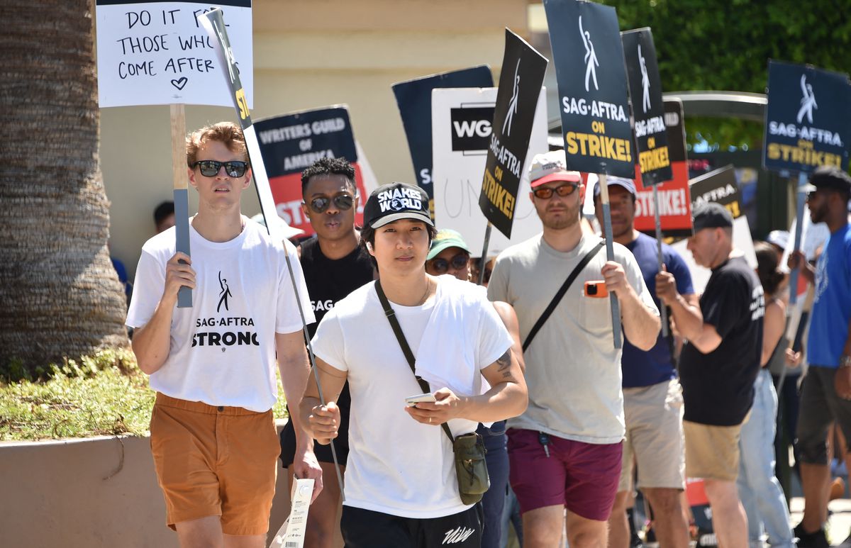 Un groupe d'acteurs et d'écrivains à Los Angeles tenant des pancartes et faisant la grève par temps chaud.