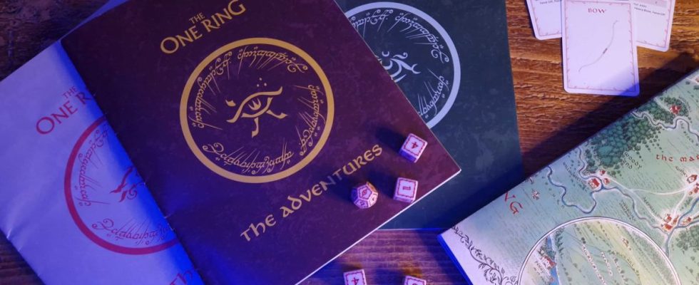 The One Ring Starter Set rulebooks, dice, cards, and map laid out on a wooden table