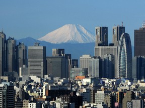 Le mont Fuji au Japon est vu en arrière-plan entre des gratte-ciel dans la région de Shinjuku à Tokyo le 4 janvier 2011.