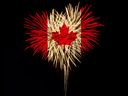 Feux d'artifice en forme de coeur avec le drapeau du Canada sur fond noir.