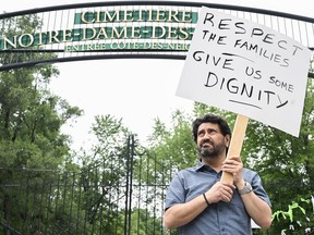 Jimmy Koliakoudakis brandit une pancarte lors d'une manifestation devant le cimetière Notre-Dame-des-Neiges à Montréal, le dimanche 9 juillet 2023.