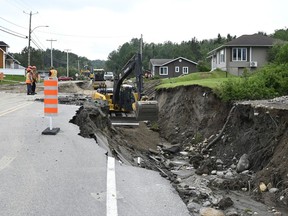 Les équipes commencent les réparations d'un tronçon délavé de la route 170 à Rivière-Éternité, au Québec, le dimanche 2 juillet 2023.