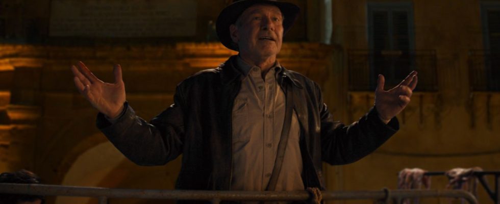 Harrison Ford gesturing with his arms as he speaks in a nighttime scene in Indiana Jones and the Dial of Destiny.