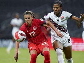 DOSSIER - Christine Sinclair (12) du Canada et Victoria Swift de Trinité-et-Tobago s'affrontent pour le ballon lors d'un match de football du championnat féminin de la CONCACAF à Monterrey, au Mexique, le 5 juillet 2022.