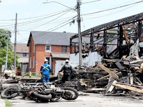 Les motos récupérées d'un club-house des Outlaws sont au premier plan mardi alors que les enquêteurs continuent de passer au crible l'épave d'un incendie sur la rue Perth à Brockville, en Ontario.
